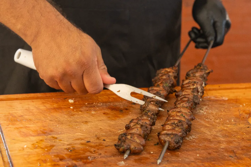 Churrasqueiro da ChurrascoShow preparando coração de frango no espeto no Rio de Janeiro